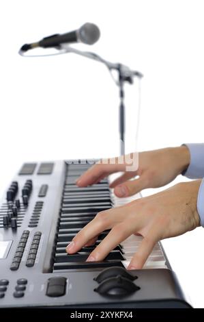 Maicrophone et mains masculines jouant du piano dans le studio isolé sur blanc, poivre peu profond de firld avec mise au point plased sur la main Banque D'Images