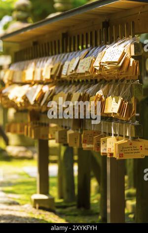 De nombreux petits panneaux ou plaques appelés étiquettes EMA en bois portant des messages écrits des visiteurs et des souhaits accrochés devant un sanctuaire shinto au Todai-ji te Banque D'Images