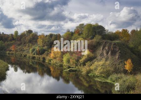 Saison d'automne avec un plan d'eau entouré d'arbres et de buissons par les différentes nuances d'orange et de jaune sur les feuilles des arbres. Calme et reflec Banque D'Images