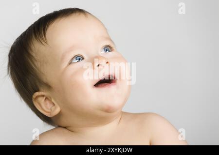 Le bébé aux yeux bleus, gros plan. fond gris Banque D'Images