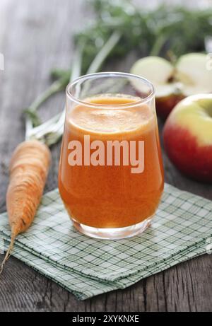 Jus frais de pommes et de carottes sur fond de bois Banque D'Images