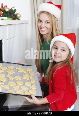 Petite fille avec sa mère baking Christmas cookies à la cuisine Banque D'Images