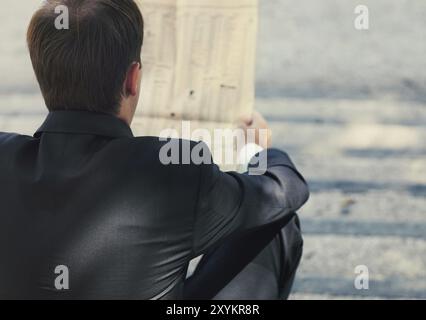 Gros plan des mains de l'homme d'affaires avec un journal sur l'escalier. À l'extérieur Banque D'Images