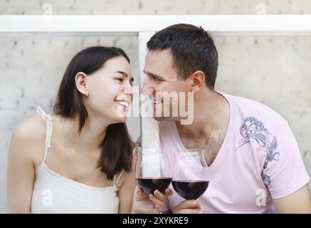 Jeune couple heureux dégustant un verre de vin rouge sur la terrasse Banque D'Images