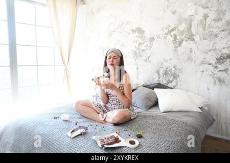 Chocoholic. Joyeuse jeune femme folle triste mangeant des bonbons dans sa chambre. Femme émotionnelle avec manger de la glace et pleurer après le divorce Banque D'Images