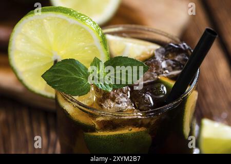 Longdrink Cuba Libre (froid) avec rhum brun et citron vert frais sur fond de bois rustique Banque D'Images