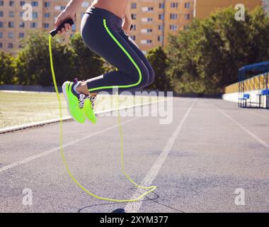 Femme avec la corde à sauter. Belle jeune femme avec une corde à sauter dans ses mains avec un stade comme arrière-plan. Close up Banque D'Images