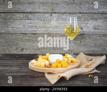 Ensemble de différents types de fromages avec un verre de vin blanc sur la table en bois Banque D'Images