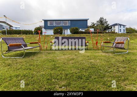 DJUPIVOGUR, ISLANDE, 21 JUIN : trois vieux canapés sont disposés à l'extérieur sur la pelouse avec une décoration orange le 21 juin 2013 à Djupivogur, Islande, Europe Banque D'Images