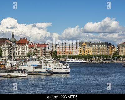 Vue sur un port animé avec plusieurs navires et bateaux entourés de bâtiments urbains sous un ciel bleu, stockholm, mer baltique, suède, scandinavie Banque D'Images