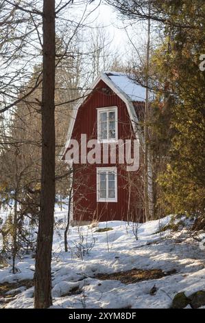 Maison en bois peinte en rouge dans un paysage hivernal en Suède Banque D'Images