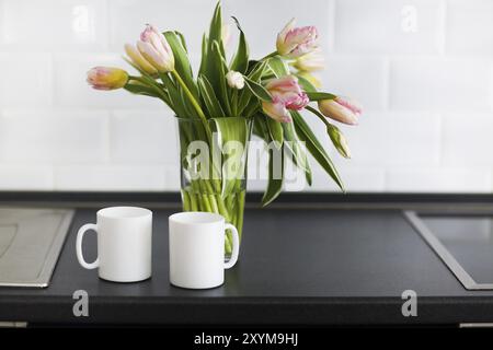 Nature morte au bouquet de tulipes roses en vase en verre sur la cuisine Banque D'Images