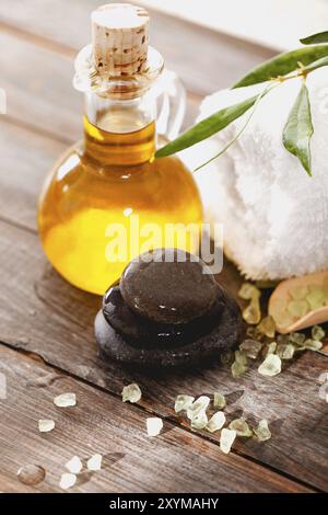 De dessus galets lisses et serviette douce placés sur la table en bois près de l'huile d'olive fraîche et du sel dans le salon de spa Banque D'Images