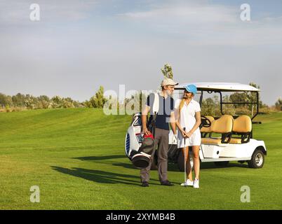 Jeune couple sportif jouer au golf sur un parcours de golf. Debout près de l'golfcar Banque D'Images