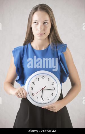 Jeune femme tenant une horloge devant son ventre. Concept d'horloge biologique Banque D'Images