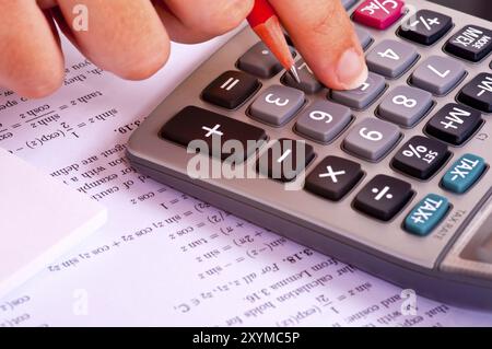 Étudiant faisant des exercices de mathématiques avec une calculatrice et un crayon rouge Banque D'Images