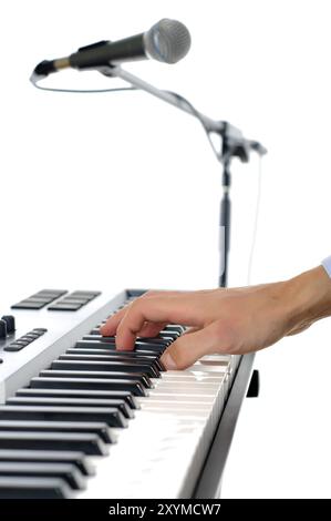 Maicrophone et mains masculines jouant du piano dans le studio isolé sur blanc, poivre peu profond de firld avec mise au point plased sur la main Banque D'Images