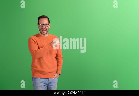 Portrait d'un vendeur joyeux pointant vers l'espace vide et le marketing de nouveau produit sur fond vert Banque D'Images