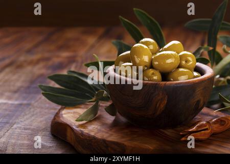 Olives vertes en bois d'bol sur fond en bois ancien. Vue de dessus avec l'espace pour le texte Banque D'Images