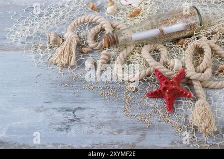 Coquillages de mer dans une résille, sur une planche de bois, fond de vacances d'été Banque D'Images