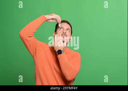 Portrait de bel homme appliquant pour traiter l'irritation tout en se tenant isolé sur fond vert Banque D'Images