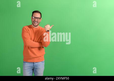 Portrait de beau vendeur extatique pointant à l'espace de copie et le marketing sur fond vert Banque D'Images