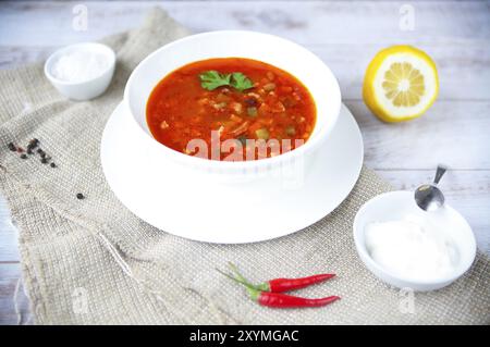 Soupe rouge avec de la crème et le persil sur table Banque D'Images