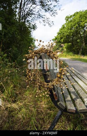 Couronne de fleurs séchées suspendue sur un banc dans un parc Banque D'Images