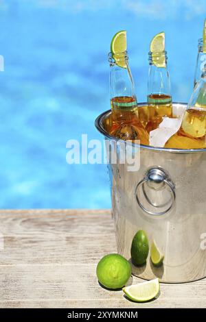 Vue rapprochée de la benne avec des cubes de glace, bouteilles de bière et de tranches de citron vert de la piscine Banque D'Images