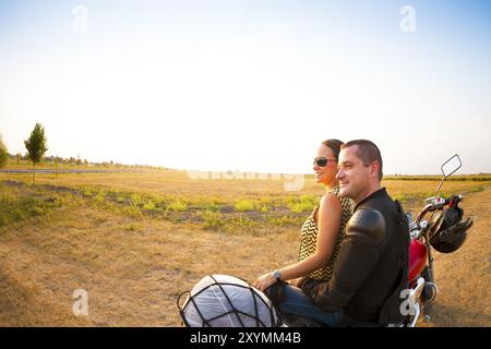 Jeune couple de motards sur la route de campagne contre le ciel Banque D'Images