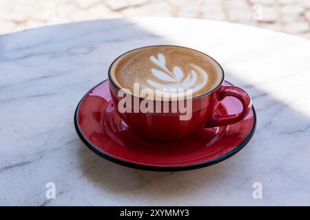 tasse de café latte avec tasse en céramique rouge sur une table de café de rue en marbre blanc Banque D'Images