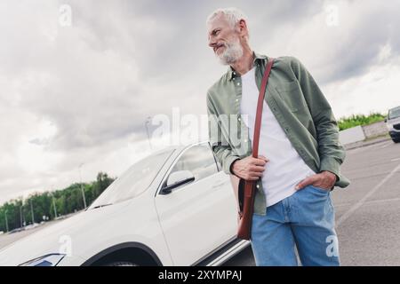 Photo de beau bon gars seniour bonne humeur porter chemise verte marchant voiture à cheval à l'extérieur de la rue urbaine de la ville Banque D'Images