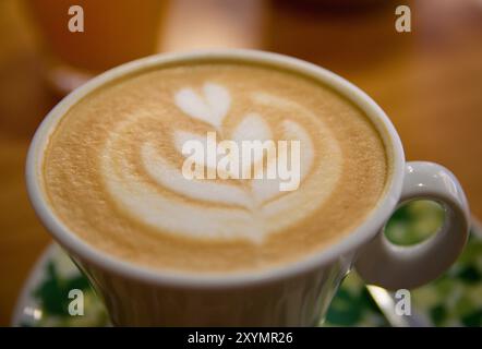 Gros plan d'une fleur dessinée à l'aide de techniques d'art latte sur une tasse de café latte lors d'un petit déjeuner dans un bar Banque D'Images
