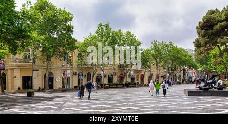 Bakou, Azerbaïdjan - 5 mai 2024 : les visiteurs profitent d'une promenade tranquille dans la rue Nizami, entourée de charmantes boutiques et d'arbres luxuriants sous un ciel nuageux, créant une atmosphère urbaine animée Banque D'Images