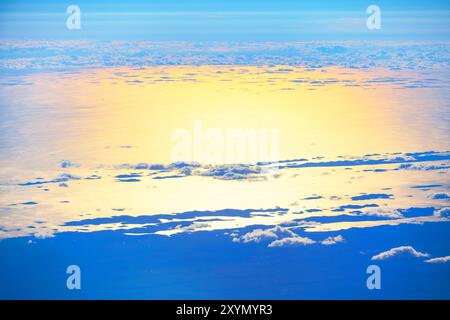 Vue aérienne montrant le vaste océan rencontrant le ciel, capturée depuis une fenêtre d'avion pendant le vol. Survoler les nuages et l'océan au crépuscule Banque D'Images
