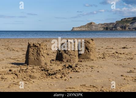 Châteaux de sable sur la plage de Runswick Sands, North Yorkshire Angleterre, Royaume-Uni, avec Kettleness en arrière-plan Banque D'Images