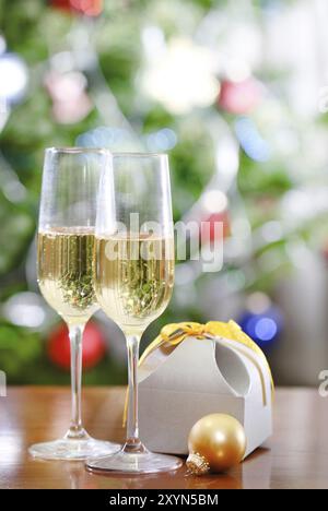 Verres de champagne et cadeau de Noël en face de l'arbre de Noël pour les vacances Banque D'Images