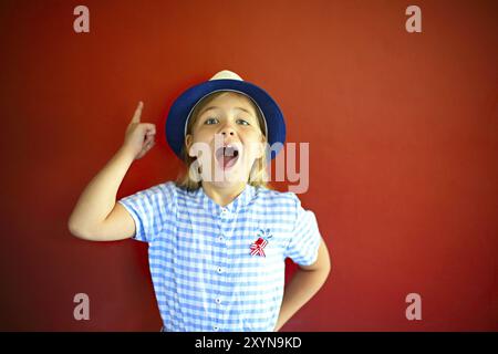 Très emothional les enfants portent un chapeau sur un fond rouge. Copie espace, lumière du jour Banque D'Images