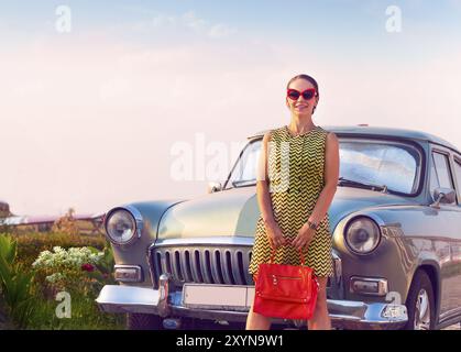 Belle brunette woman standing près de voiture rétro Banque D'Images