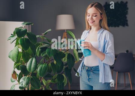 Photo de jolie jeune femme joyeuse porter chemise décontractée appréciant le nettoyage du week-end à l'intérieur de la maison de maison de chambre Banque D'Images