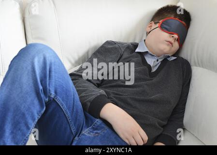 L'adolescent dort pendant la journée dans un masque pour dormir Banque D'Images