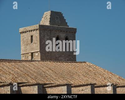 Tour historique en pierre d'une église avec un toit de tuiles rouges sous un ciel bleu clair, ibiza, mer méditerranée, espagne Banque D'Images