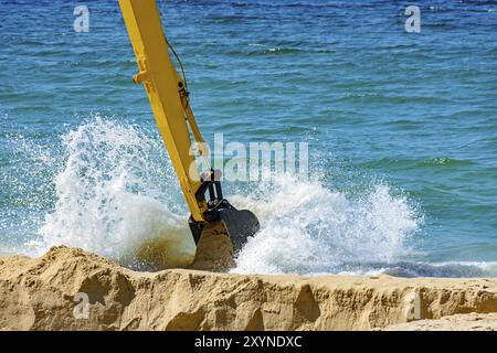 Retrait de la pelleteuse de la plage de sable et à jouer dans l'eau de mer qui finit par éclabousser Banque D'Images