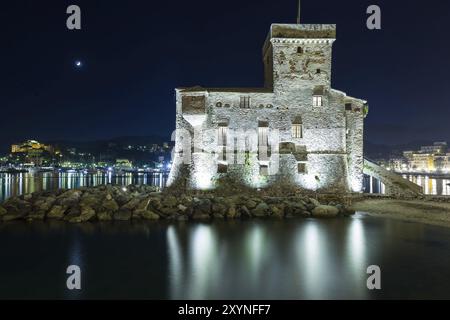 L'ancien château de Rapallo, construit sur la mer ligure illuminé par la nuit Banque D'Images