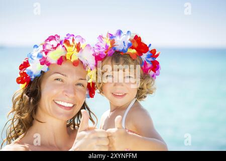 Famille heureuse montrant le signe pouce vers le haut sur fond bleu de mer. Concept de vacances d'été Banque D'Images