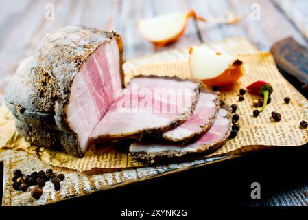 Saindoux fumé, bacon, un demi-morceau, sur une planche de bois brun. Vue de dessus Banque D'Images