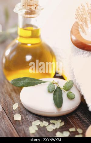 Serviette douce placée sur la table de bois d'œuvre près de l'huile d'olive fraîche et du sel dans le salon de spa Banque D'Images