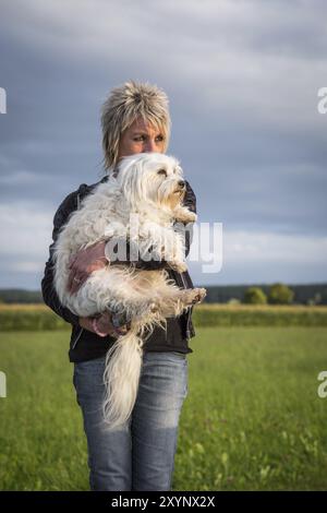 Une femme tient son petit chien blanc dans ses bras Banque D'Images