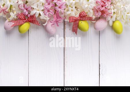 Fond de Pâques avec des œufs colorés, des fleurs de jacinthe et des rubans sur planche de bois blanc Banque D'Images