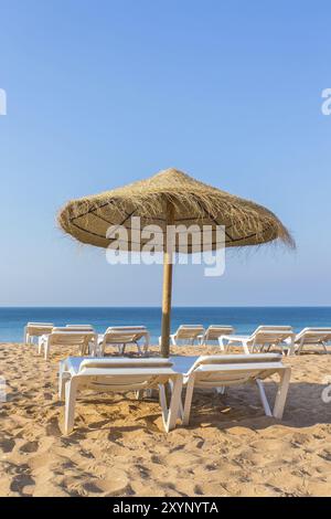 Un parasol de plage en osier avec des lits de plage du blue sea Banque D'Images